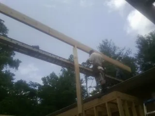 Carpenter setting a ridge beam over a new addition frame — Ice Dam Removal by Roofing Brothers in Leoma