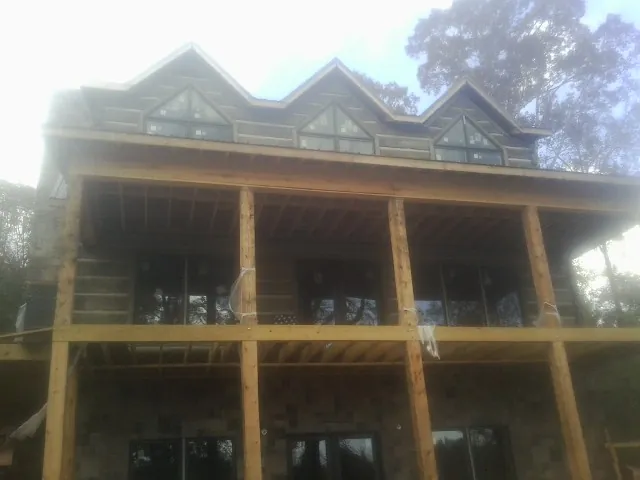 Dormers and porch framing on a large log home under construction — Roof Coating work by our crew in Leoma