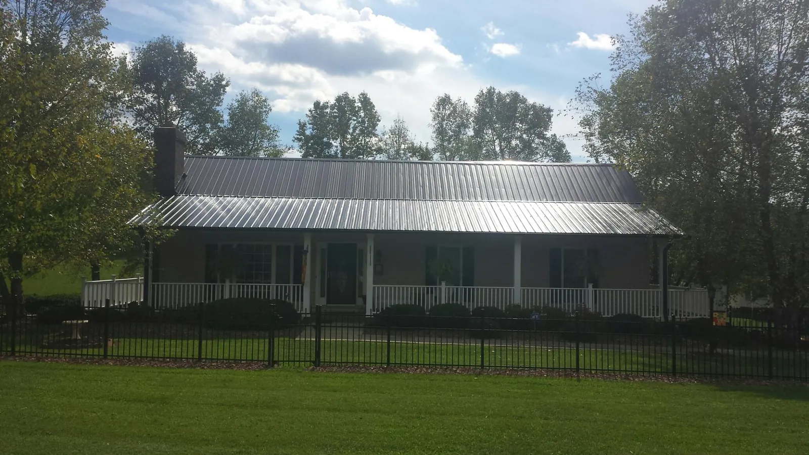 Gray metal roof on a brick ranch with a full width front porch — Gutter Guard Installation work by our crew in Leoma