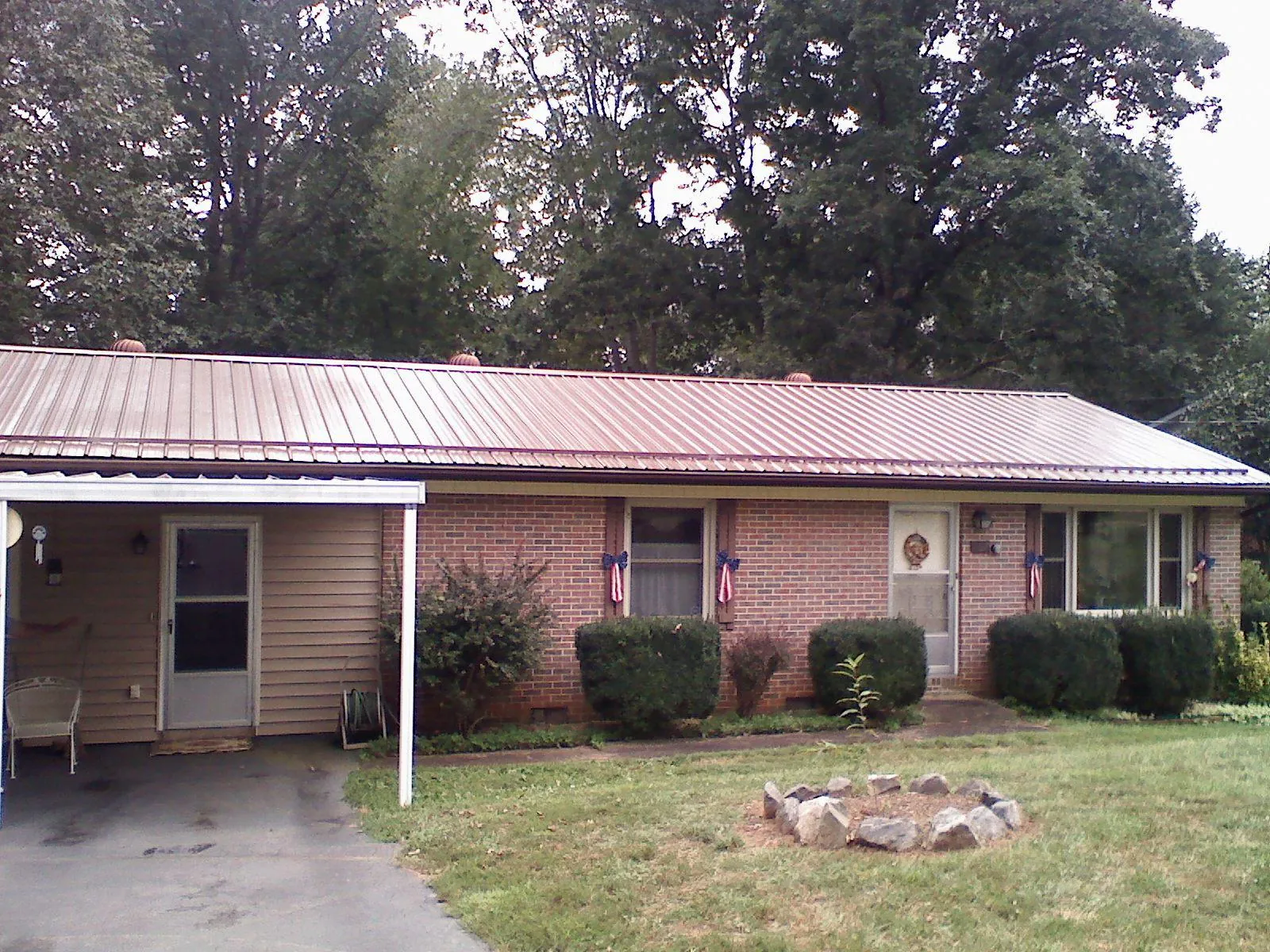 Bronze metal roof and carport on a brick ranch home — Roof Repair work by our crew in Leoma