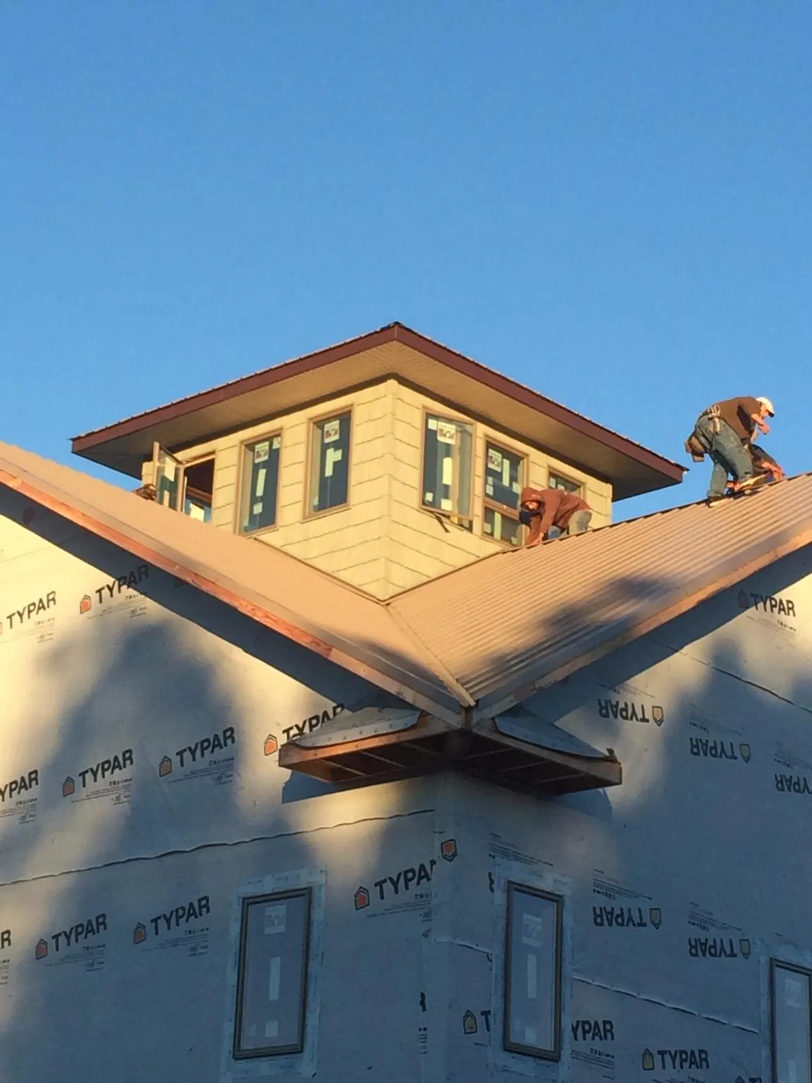 Roofers working around a rooftop cupola on a new metal roof at sunset — Roof Waterproofing in Leoma by Roofing Brothers